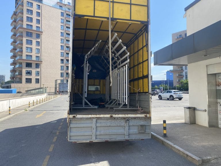 Güneşli nakliyat hizmetinde kamyon kasasına sanayi tipi metal çerçeve ve üretim ekipmanlarının güvenli şekilde yüklenmesi